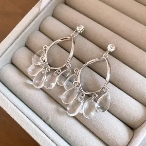 Detailed view of silver resin earrings with clear water drop tassels in a box