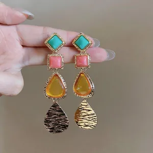 Primer plano detallado de pendientes colgantes geométricos vintage en varios colores