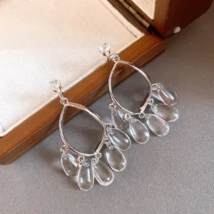 Close-up of clear resin water drop tassel earrings with premium silver needle finish