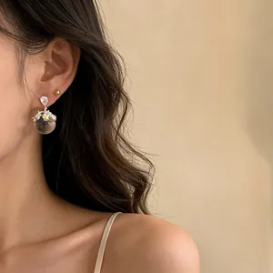 Detailed view of elegant silver needle earrings featuring a floral resin ball pendant