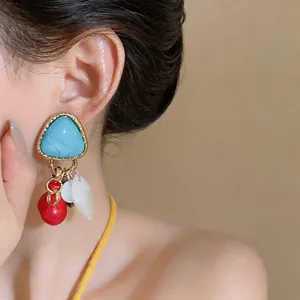 Primer plano detallado de pendientes vintage estilo palacio con resina azul y conchas