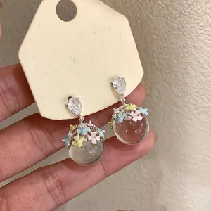 Detailed shot of resin sphere drop earrings with colorful enamel flowers and crystals.
