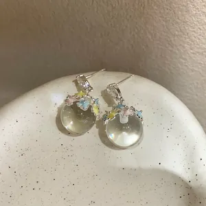 Close-up of elegant star resin globe earrings with silver needle and rhinestones