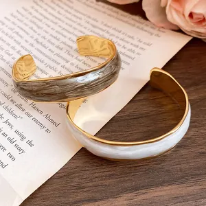 Close-up detail of 18K gold plated cuff bracelets with wavy enamel marble patterns