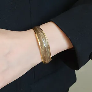 Macro view of 18K gold plated wavy stripe open bangle with retro enamel finish.