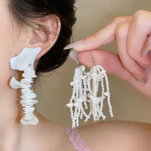 Detailed view of French-style white shell fringe earrings with pearl bead tassels