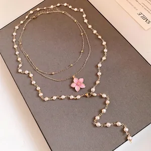 Elegante mehrlagige Goldhalskette mit weißen Kunstperlen und rosa Blumenanhänger