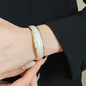 Detailed close-up of a white enamel wavy bangle featuring 18K gold plated edges