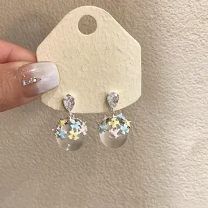 Close-up view of elegant silver needle earrings with CZ stones and colorful enamel flowers
