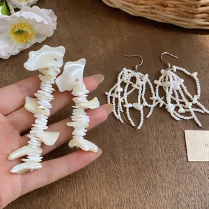 Close-up of elegant French shell tassel earrings with white natural textures