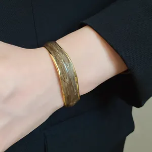 Detailed view of an 18K gold plated open bangle featuring a brown wavy oil drip design.