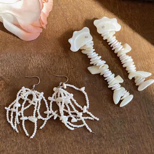 Close-up detail of elegant white shell tassel earrings and unique bone drop earrings