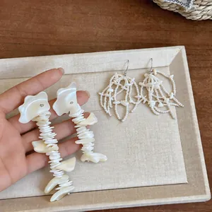 Detailed view of French-style white shell tassel earrings presented on a display tray