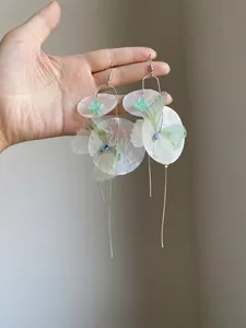 Macro shot of elegant long tassel earrings with shell discs and chiffon butterflies