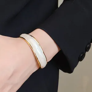 Elegant close-up of an 18K gold plated wavy stripe enamel open bangle bracelet on wrist