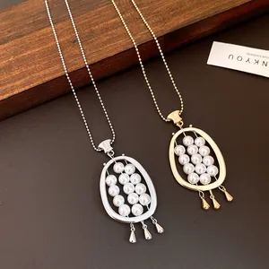 Close-up detail of retro oval pearl pendants in gold and silver finishes with tassels.