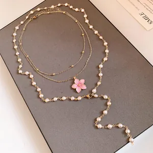 Elegante mehrlagige Goldkette mit rosa Blumenanhänger und weißen Perlen im Detail