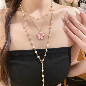 Mehrlagige goldfarbene Halskette mit rosa Blumenanhänger und eleganten Perlenketten.