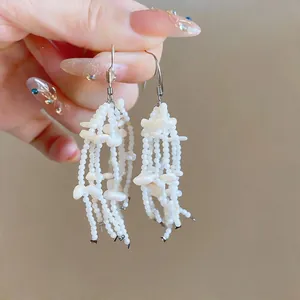 Detailed macro view of elegant French style white shell tassel earrings with hooks
