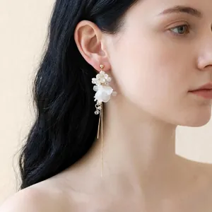 Gros plan détaillé de boucles d'oreilles style français avec fleurs blanches et perles.