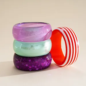 Macro detail of colorful resin bangles featuring striped, pearlescent and glitter styles
