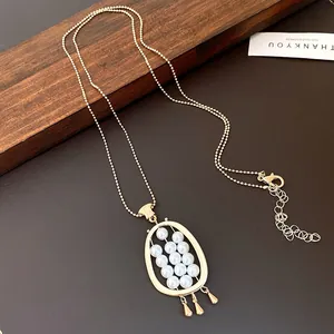 Detail view of a vintage oval gold pendant necklace featuring elegant small white pearls