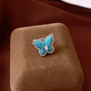 Close-up detail of a silver butterfly ring with turquoise beads and a central zircon