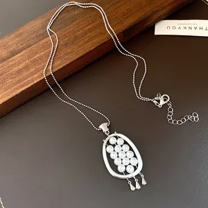 Close-up of retro silver oval necklace with pearl cluster on leather background