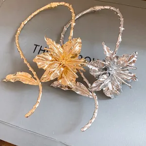 Close-up of gold and silver metallic pleated flower chokers on a gray textured base.