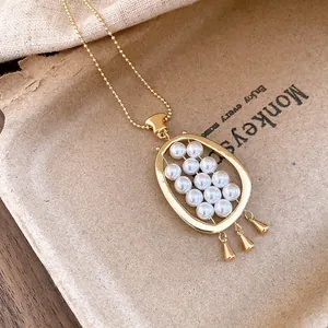 Detailed macro view of a vintage oval gold-toned pendant necklace with multiple pearls
