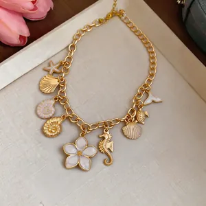 Close-up of a gold vacation necklace with seashell, seahorse, and floral enamel pendants.