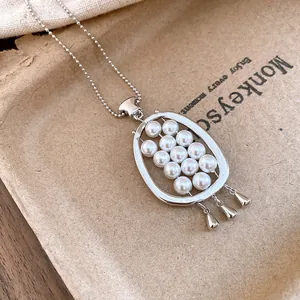 Close-up detail of a retro oval necklace pendant inlaid with pearls and teardrop charms