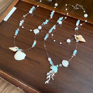 Blue ocean style necklace with shell starfish and pearl pendants on elegant wooden tray