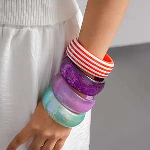 Detailed view of colorful dopamine resin striped and glitter chunky bracelets on model's wrist