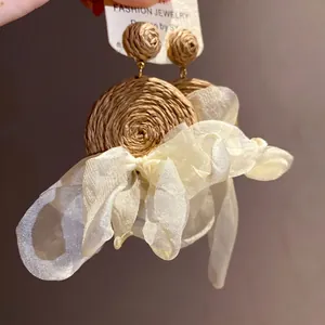 Elegantes pendientes colgantes redondos de rafia tejida con lazos de gasa blanca y plata