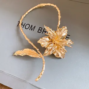 Close-up of golden metal lily flower choker with textured leaf stem detail