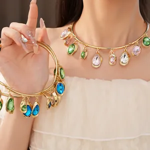 Close-up of a gold teardrop choker necklace with colorful oval gems on a model