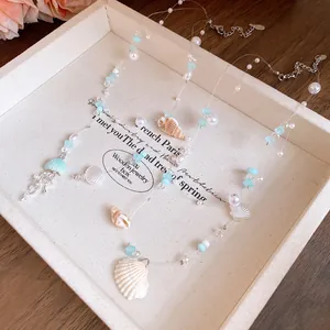 Close-up detail of the beach-themed necklace featuring pearls, blue beads, and shells
