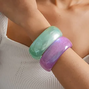 Detail shot of mint green and purple glitter resin bangles worn on a model's wrist