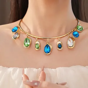 Close-up of a gold-tone choker necklace featuring colorful crystal teardrops
