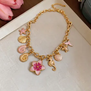 Close-up of a gold-toned necklace with colorful shell, seahorse, and flower pendants.