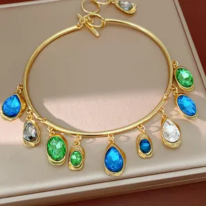 Close-up detail of a gold choker featuring colorful teardrop and oval gemstone charms