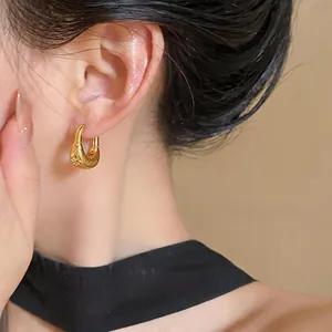 Detailed close-up of 18K gold plated U-shaped earrings with textured surface.