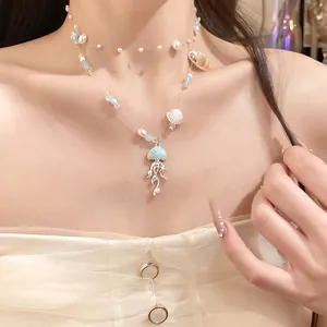 Close-up detail of elegant blue jellyfish pendant and pearl layered necklace on model