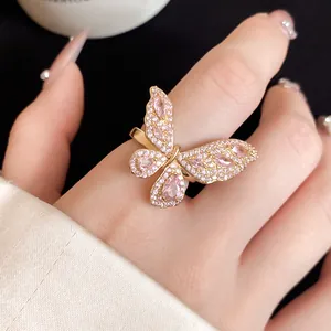Dettaglio di un elegante anello a farfalla dorato con pietre rosa e zirconi incastonati