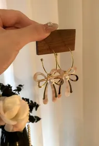 Primo piano di eleganti orecchini in oro a forma di C con fiocco rosa e perla