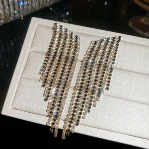 Macro view of luxurious silver needle rhinestone tassel earrings on a textured display tray