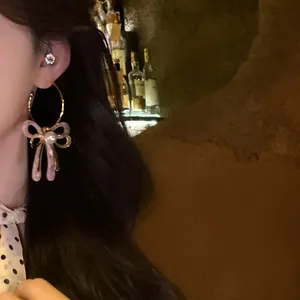 Eleganti orecchini con fiocco in acetato rosa e perla indossati dalla modella.