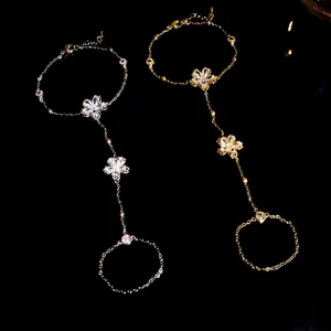Detailed view of gold and silver plated flower zircon slave bracelets on black.
