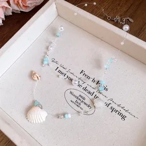 Detailed view of the ocean-themed shell and faux pearl necklace with blue accents